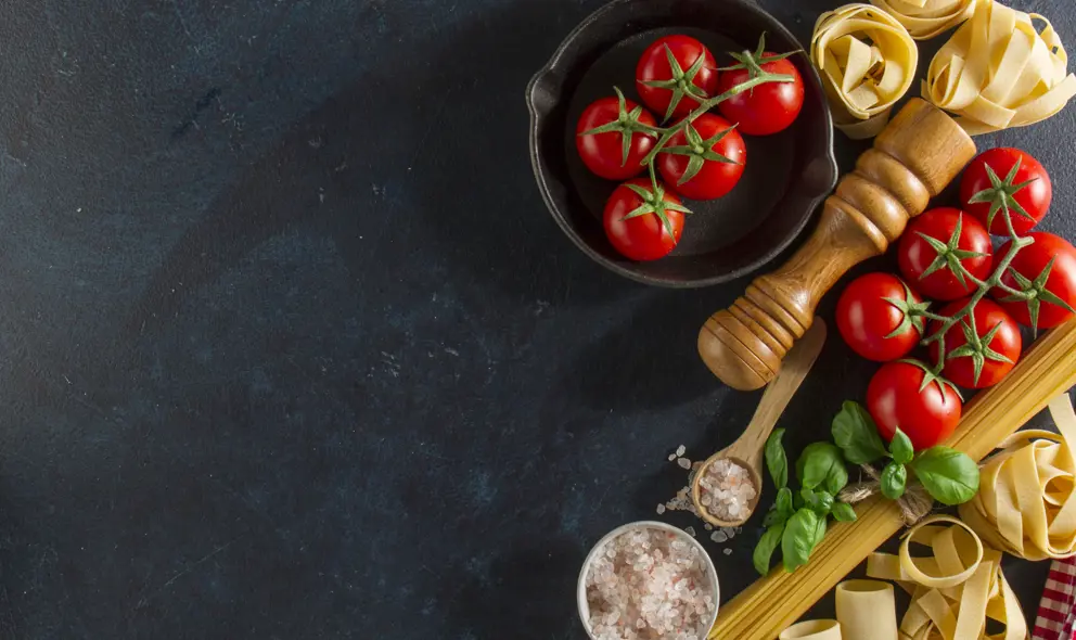 Table with fresh tomatoes, salt and pasta
