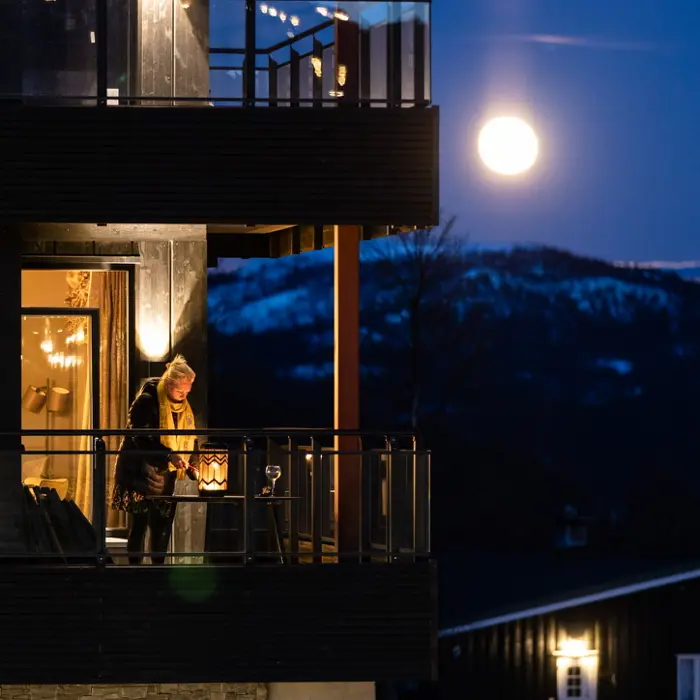 Kveldsbilde hvor en kvinne koser seg på et av hotellets rom sin balkong